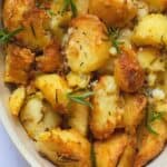rosemary infused roast potatoes in a baking dish on a white marble background