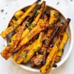 mustard maple glazed parsnips in white bowl on backdrop