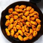 Sweet Potato Gnocchi in black frying pan. Pan is displayed on white background.