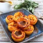 Yorkshire puddings towered on a blue/black plate covered in gravy.