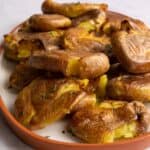close up of smashed potatoes on white plate with orange edge.