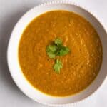 Carrot & Coriander Soup served in a white bowl with coriander on top.