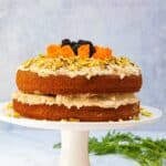 carrot cake on white cake stand with grey marbled background.