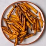 sweet potato fries on white plate with orange rim.