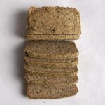 Overhead shot of sliced seeded bread on white surface.