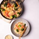 Vegan Pad Thai served in a plate next to a pan on the table.