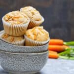 Vegan Carrot Cake Cupcakes in a bowl with carrots in the background.