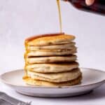 Pouring Maple syrup over gluten free pancakes.