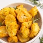 air fryer roast potatoes served in a white bowl with fresh rosemary.