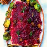 baked christmas salmon served with cranberry sauce an brussels sprouts on a white plate.