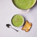 Pea Soup topped with chilli flakes with a slice of toasted bread.
