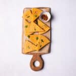 Socca flatbread slices into triangles, served on a wooden board.
