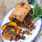 stuffed butternut squash on a white plate, sliced open