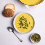 cauliflower soup served with bread rolls and pumpkin seeds.