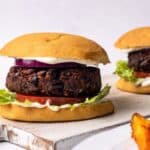 mushroom burgers in a bun with potato wedges on the side.