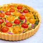 vegan quiche with a crispy pastry served on a marble worktop.