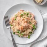 salmon risotto with peas served on a white plate.
