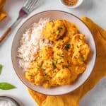 cauliflower curry served in a white bowl with rice.