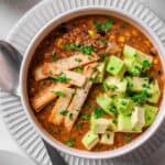 mexican soup with sliced avocado on top.