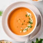 sweet potato soup garnished with parsley and cashews.
