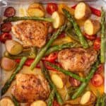 Roasted chicken thighs with vegetables on a pan.