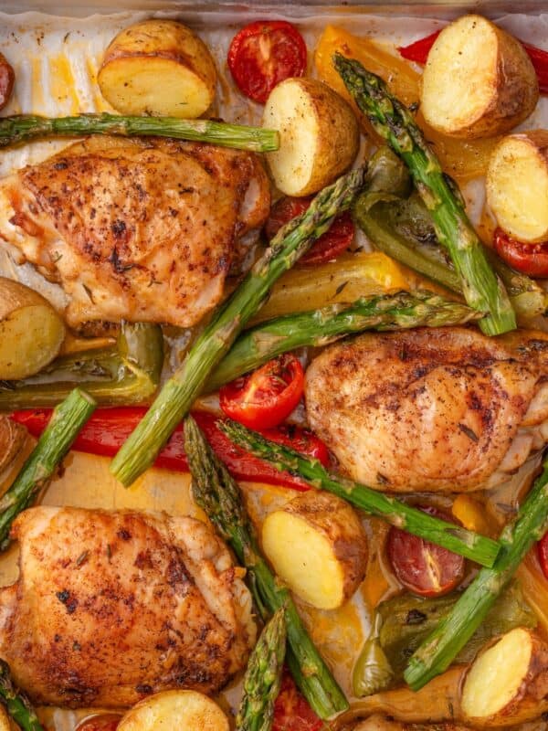 Roasted chicken thighs with vegetables on a pan.