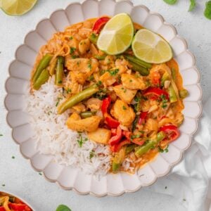 Assorted fresh ingredients for preparing a healthy Thai red curry, featuring white fish, rice, green beans, vegetables, and aromatic herbs.