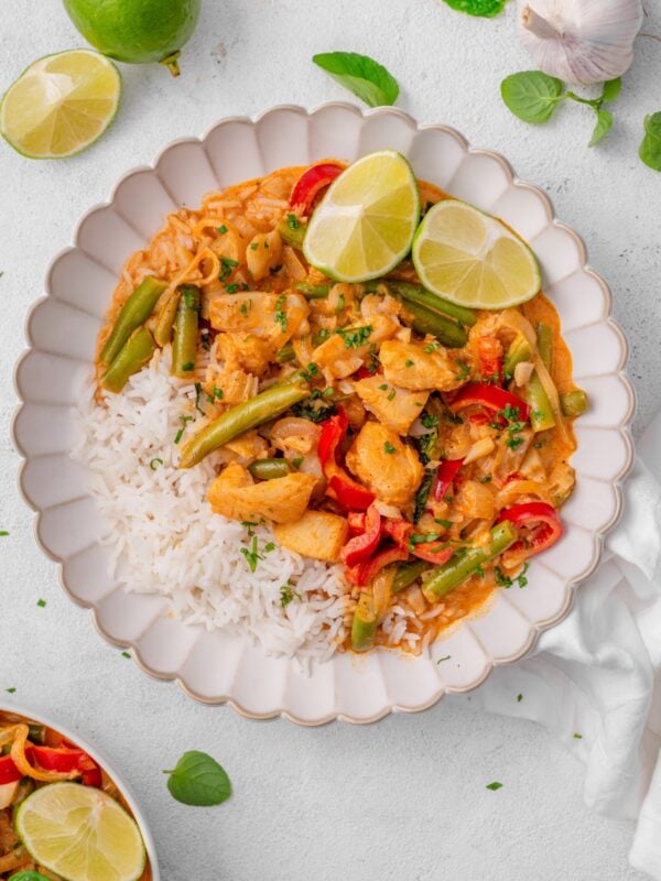 Assorted fresh ingredients for preparing a healthy Thai red curry, featuring white fish, rice, green beans, vegetables, and aromatic herbs.
