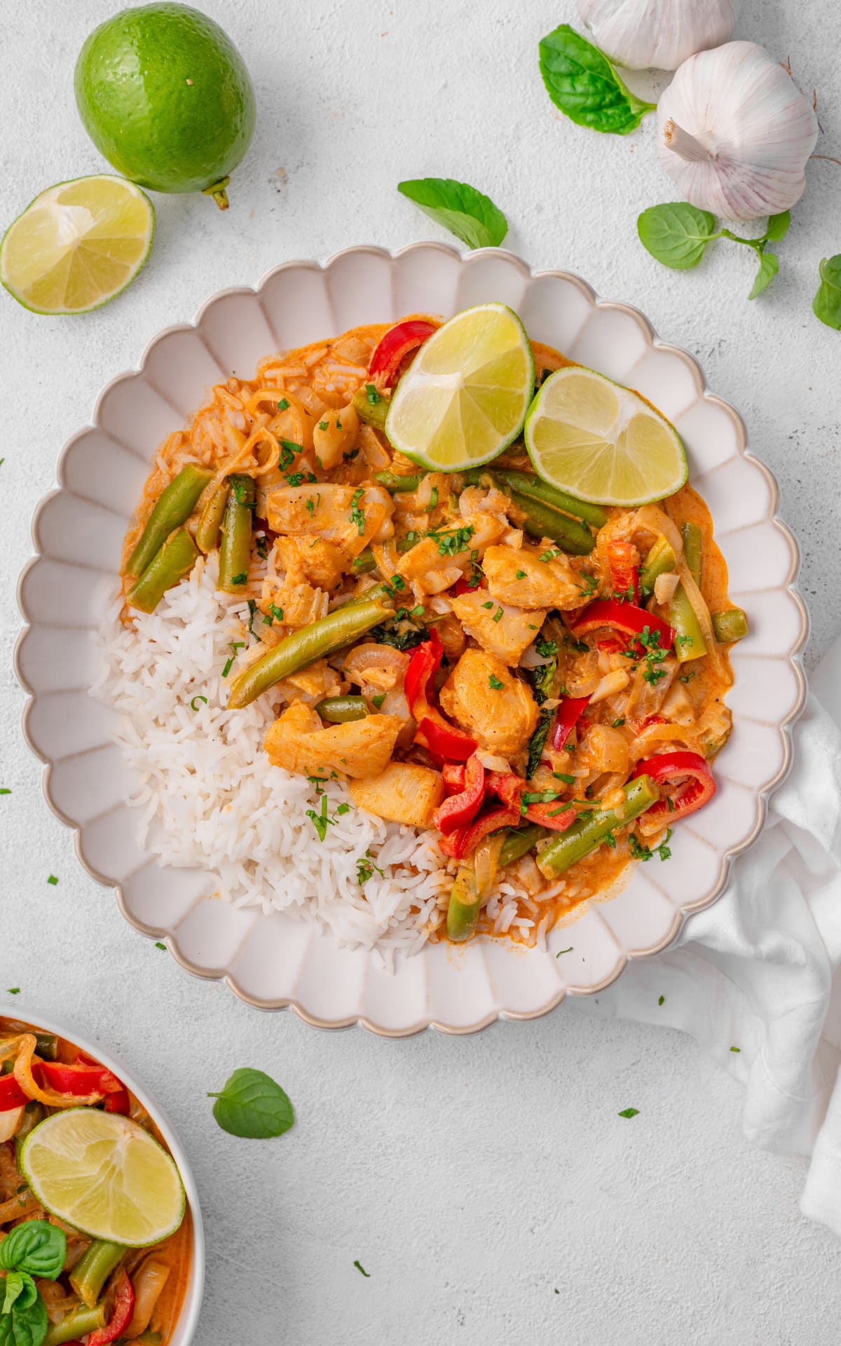 Assorted fresh ingredients for preparing a healthy Thai red curry, featuring white fish, rice, green beans, vegetables, and aromatic herbs.