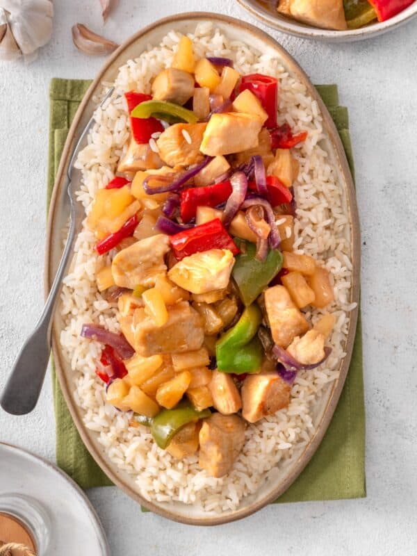 sweet and sour chicken served on a plate with rice.