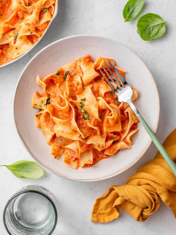 Creamy Roasted Red Pepper and Tomato Pasta served in a bowl with fresh basil